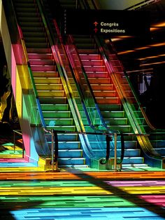 an escalator with multiple colored stairs in the background