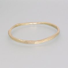 This simple bangle made of brass captivates with its simple, rustic, yet appealing form. The piece was hand-forged and then poured off into a mold. It was then hammered to create its irregular and unique appearance, with each copy having a subtly different look. This bangle is a great accessory for everyday wear and can also be a successful complement to our various casting rings. Dimensions: Size: approx. 7.87 inch, 20 cm  Width: 0.08-0.16 inch, 2-4 mm  Thickness: 0.08-0.16 inch, 2-4 mm Minimalist Hand Forged Brass Bracelets, Minimalist Hand Forged Gold Bangle, Gold Minimalist Hand Forged Bangle, Rustic Hammered Gold Jewelry, Hammered Yellow Gold Brass Bangle, Simple Bangle, Brass Bangle, Bangles Making, Copper Hair