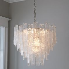 a chandelier hanging from the ceiling in a room with white walls and windows