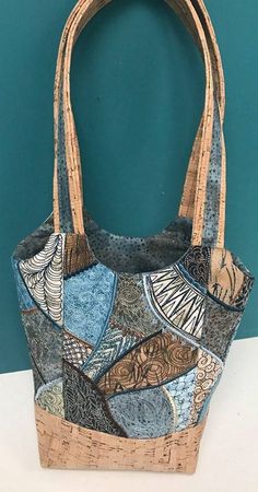 a handbag made out of fabric and cork is sitting on a white table next to a blue wall