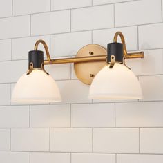 two light bathroom fixture with white and black shades on brick wall in public restroom area