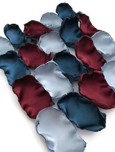 several pieces of satin fabric are arranged in a pattern on a white surface, including red and blue