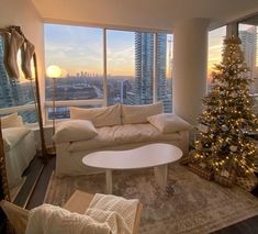 a living room filled with furniture and a christmas tree in front of a large window