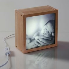 a small wooden box with a baby's photo on it and a cord plugged in