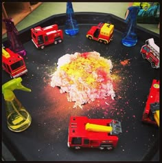 toy firetrucks and other toys on a play tray with water, sand, and glue