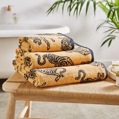 three towels are stacked on top of each other in front of a bathtub and potted plant