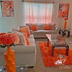 a living room filled with furniture and orange flowers in vases on the coffee table