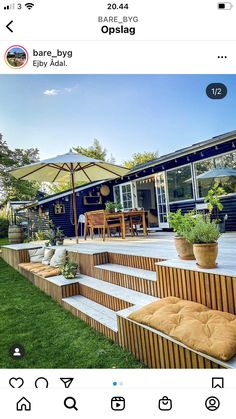 an instagram photo of a patio with seating and umbrellas on the grass, in front of a house