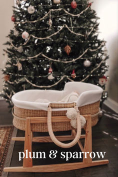 a baby's cradle in front of a christmas tree with the words plum & sparrowow on it