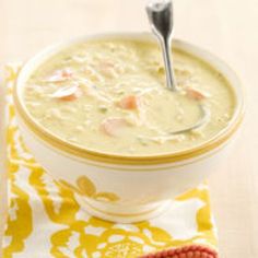 a white bowl filled with soup on top of a yellow and white table cloth next to a spoon