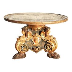 an ornately carved table with marble top and gold leaf decoration on the base, against a white background