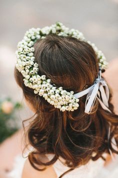 a close up of a woman wearing a white flowered headpiece with ribbon around her hair