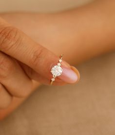 a woman's hand with a diamond ring on her thumb and the tip of her finger