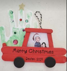 a handprinted christmas ornament with a red truck holding a child's hand