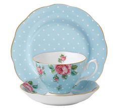 a polka dot tea cup and saucer set with pink roses on the side, sitting next to each other