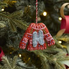 an ornament hanging from a christmas tree decorated with red and blue sweaters