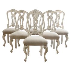 four white chairs with beige upholstered seats