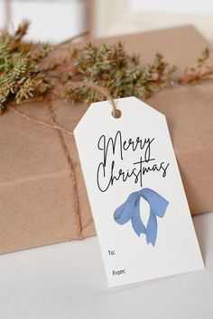 a gift wrapped in brown paper with a blue ribbon and merry christmas tag on it