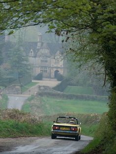 a yellow sports car driving down a country road