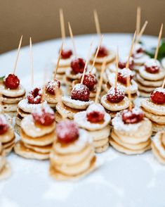 small desserts are arranged on a plate with toothpicks sticking out of them