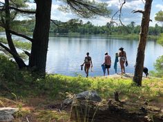 three people walking along the shore of a lake