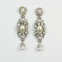 two pairs of earrings with pearls and crystal stones on them, one is white the other is silver