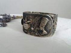 Vintage 1960s costume bracelet ,silvertone metal egyptian motifs. Measures length :8'' width: 2'' condition: excellent Shipping Is Avaliable Worldwide. Every item is carefully shipped Priority via Air Mail - shipping takes from 7 to 14 working days, depending on your location. Shipping includes Tracking. Come and check out our shop to see all items! https://www.etsy.com/shop/Themagicstories?ref=hdr_shop_menu Thanks! Note: m i n t : pristine with no signs of wear- possibly deadstock e x c e l l e Nickel-free Antique Silver Metal Cuff Bracelet, Silver Etched Metal Cuff Bracelet, Etched Silver Metal Cuff Bracelet, Antique Silver Metal Bracelets, Antique Silver Metal Bracelet, Vintage Silver Cuff Bracelet With Engraving, Handmade Antique Silver Metal Cuff Bracelet, Vintage Silver Engraved Cuff Bracelet, Silver Metal Cuff Bracelet For Ceremonial Occasions