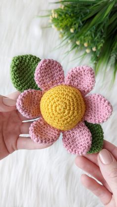 a crocheted flower is being held in someone's hand