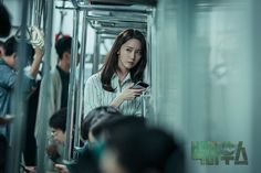 a woman is looking at her cell phone while riding the subway train with other people