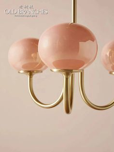 three pink glass balls hanging from a brass chandelier