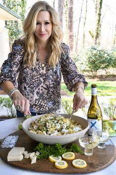 a woman standing in front of a bowl of food on top of a wooden cutting board