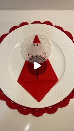 a white plate topped with a santa clause on top of a red doily covered table