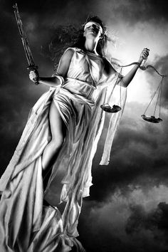 a lady justice statue holding two scales in front of a dark sky with clouds behind her