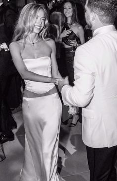 a man and woman dancing together at a formal event with other people in the background