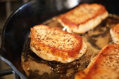 four pieces of meat cooking in a frying pan