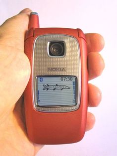 a person holding a red cell phone in their hand