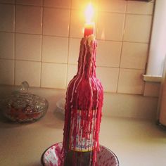 a candle that is in the shape of a bottle with blood on it sitting on a plate