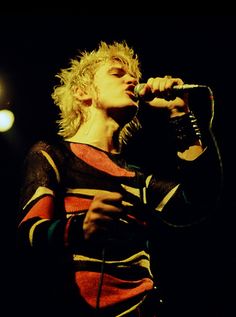 a man with blonde hair singing into a microphone