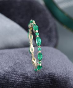 a close up of a ring with green stones