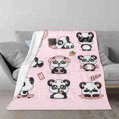 a pink blanket with pandas and other cartoon animals on it's back, in front of a couch