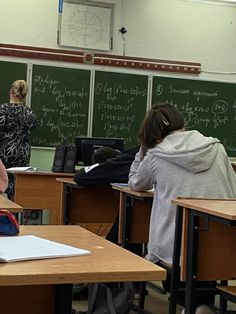 students are sitting at their desks in front of the chalkboard with writing on it