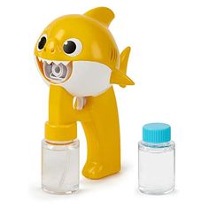 a yellow toy shark with mouth open next to an empty glass bottle and plastic container