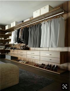 an organized closet with clothes and shoes on the shelves, along with a large ottoman