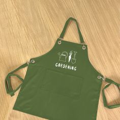 an apron with the words gardening on it sitting on top of a wooden table next to a knife and fork