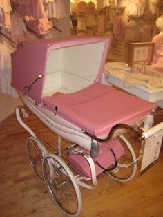 a pink and white baby carriage sitting on top of a wooden floor