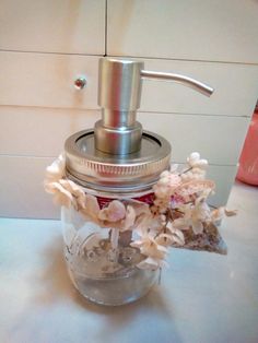 a soap dispenser sitting on top of a counter next to some flowers