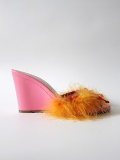 a pair of pink shoes with orange feathers on them