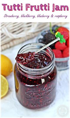 a jar filled with fruit jam next to lemons and raspberries