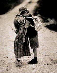 two children kissing each other on a dirt road