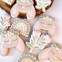 cookies decorated with pastel pink and white icing are sitting on a table next to a piece of wood